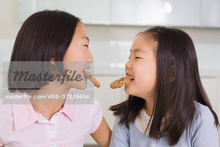 Two cheerful young girls enjoying cookies in the kitchen