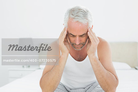 Mature man suffering from headache in bed at home
