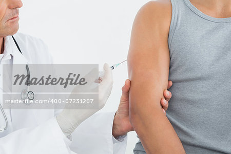 Close-up mid section of a male doctor injecting a patients arm over white background