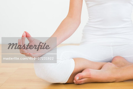 Close-up of a cropped toned woman in lotus pose at a fitness studio