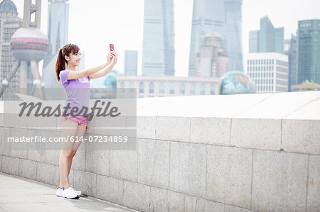 Young woman taking photograph in Shanghai, China