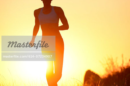 Silhouette of young woman running at sunset
