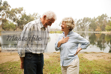 Husband and wife sharing joke by the lake