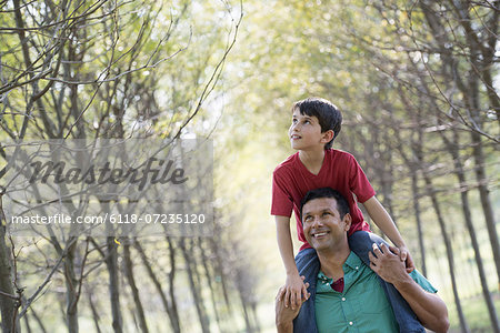 A boy having a piggyback, riding on a man's shoulders.