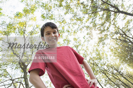 A young boy in the woodland, looking around curiously.