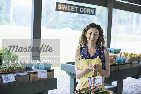 An organic fruit and vegetable farm. A woman carrying a basket of produce.