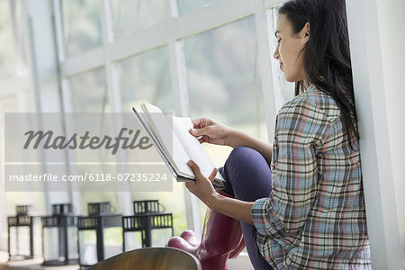 A young woman sitting reading a book.