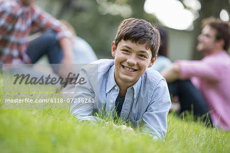A boy sitting on the grass, at a summer party.