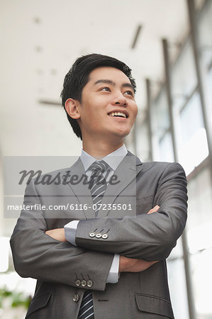 Young businessman with arms crossed smiling, portrait