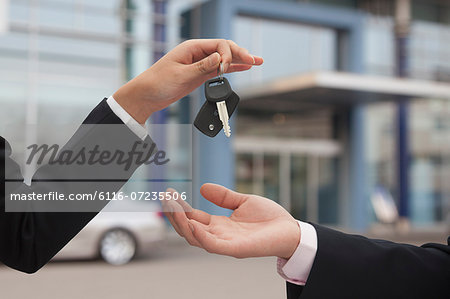 Salesman handing over car keys, close up on hands