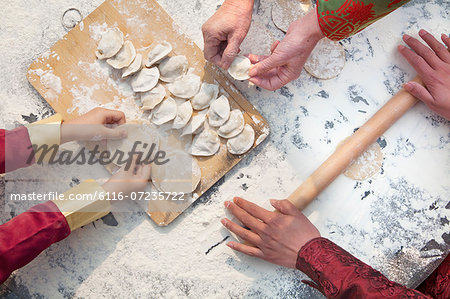 Three generation of women making dumplings, hands only