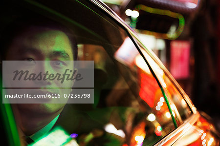 Contemplative Businessman in the back seat of a car looking out through window at night, Beijing