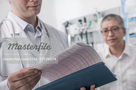 Doctor checking medical chart with patient in the background