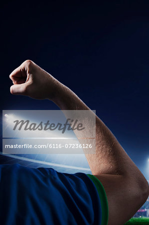 Soccer player flexing bicep in a stadium at night time