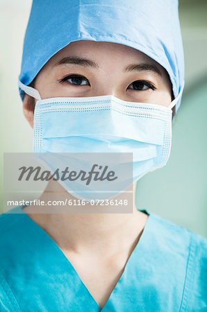 Portrait of young female surgeon wearing surgical mask in the operating room, close- up