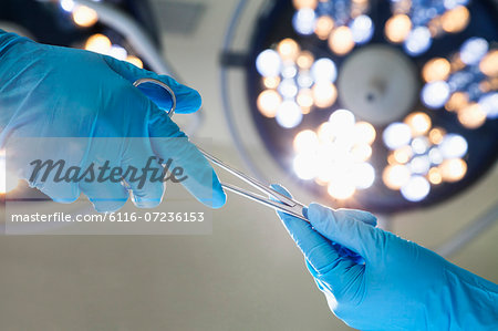 Close-up of gloved hands passing the surgical scissors, operating room, hospital