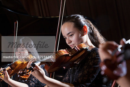 Violinists playing during a performance, head and shoulders