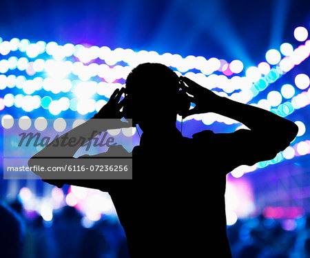 Silhouette of DJ wearing headphones and performing at a night club