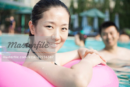 Portrait of smiling young women in the pool with an inflatable tube