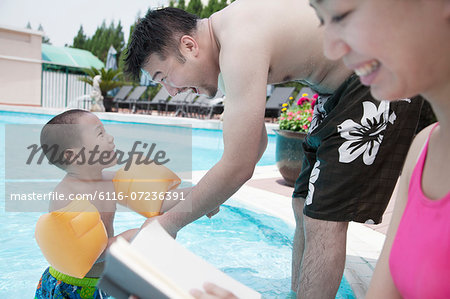 Young happy family relaxing by the pool on vacation