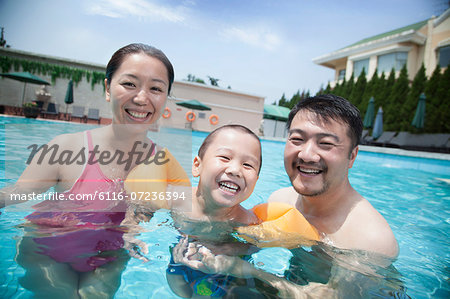 Portrait of smiling young family in the pool on vacation
