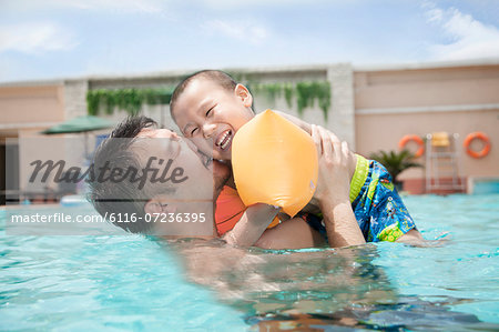 Portrait of father embracing his smiling son in the pool