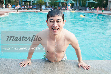 Portrait of smiling man exiting the pool and looking at camera