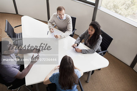 Four business people sitting at a conference table and discussing during a business meeting