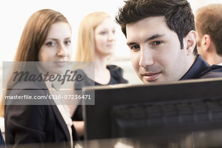 Four coworkers sitting and discussing in the office by the computer monitors