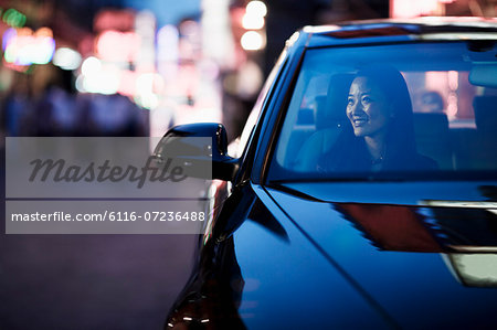 Smiling woman looking through car window at the city nightlife