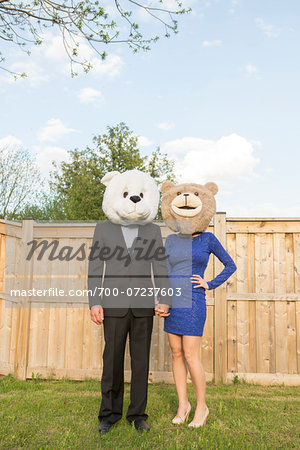 Portrait of couple standing in backyard dressed in formal attire, covering faces wearing costume bear heads, Canada Portrait of couple standing in backyard dressed in formal attire, covering faces wearing costume bear heads, Canada