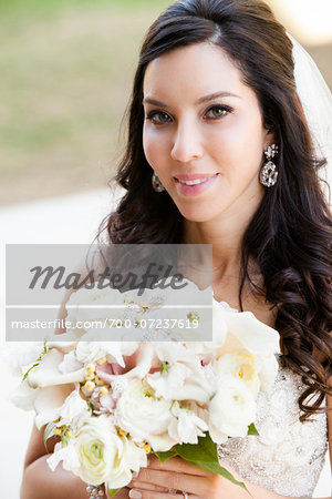 Close-up portrait of Bride in wedding gown, standing outdoors on Wedding Day, smiling and looking at camera, Canada