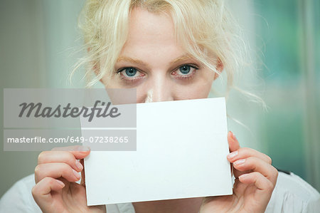 Young woman holding a blank card over her face