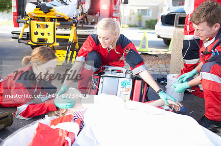 Three paramedics with patient on stretcher wearing oxygen mask