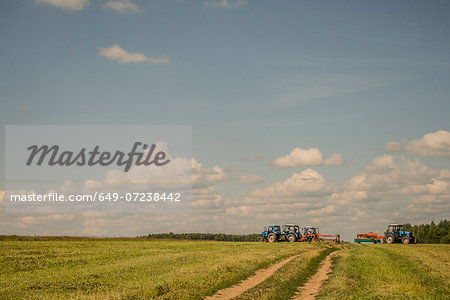 Tractors harvesting field