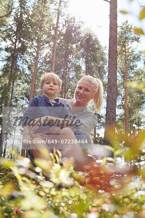 Boy sitting on mother's lap in forest