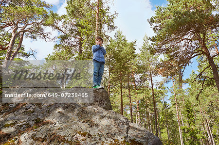 Boy standing on top of rock