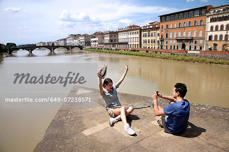 Man photographing woman with Ponte alle Grazie in background, Florence, Tuscany, Italy Man photographing woman with Ponte alle Grazie in background, Florence, Tuscany, Italy