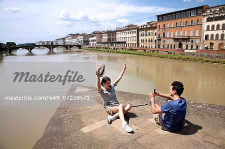 Man photographing woman with Ponte alle Grazie in background, Florence, Tuscany, Italy