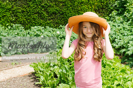 Girl wearing straw hat in garden