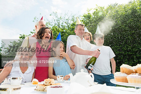 Family celebrating birthday, man opening champagne