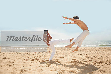 Men doing capoeira on beach