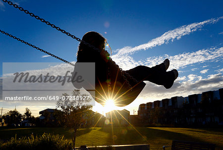Young girl on swing at sunset