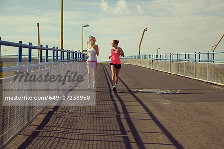 Young female joggers running on bridge