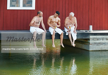 Three male friends sharing a beer outside sauna