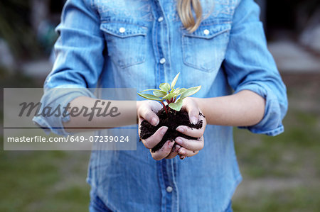 Close up of girl holding plant in pot soil Close up of girl holding plant in pot soil