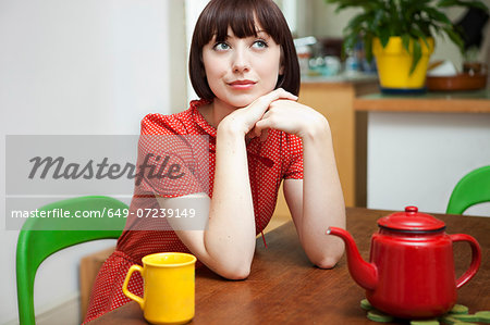 Portrait of young woman sitting at kitchen table