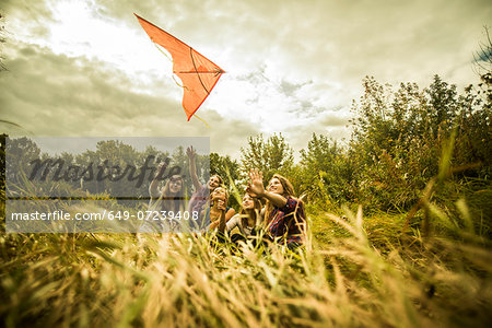 Five young women having fun with kite in scrubland