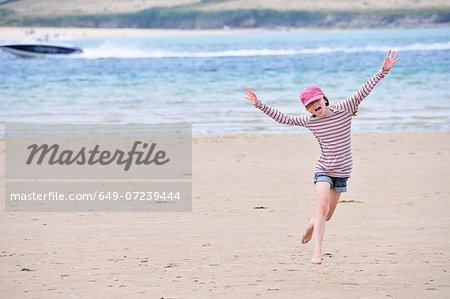 Girl running on beach, Daymer Bay, Cornwall, England, UK