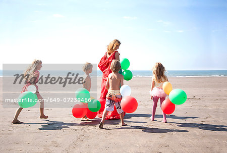 Mother with four childen on beach with balloons, Wales, UK